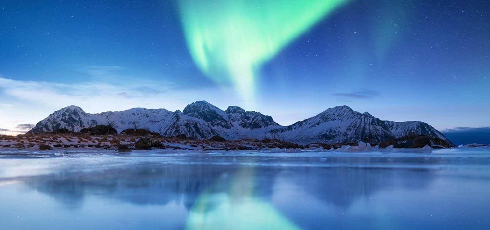 Aurora borealis on the Lofoten islands, Norway. Green northern lights. Night sky with polar lights. Night winter landscape with aurora and reflection on the ice surface. Natural background in the Norway