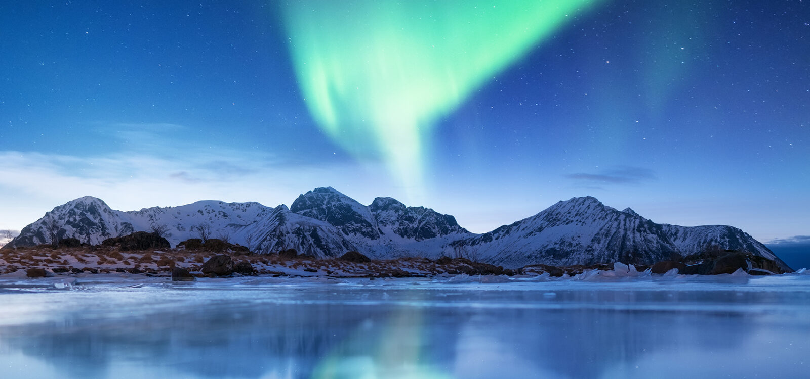 Aurora borealis on the Lofoten islands, Norway. Green northern lights. Night sky with polar lights. Night winter landscape with aurora and reflection on the ice surface. Natural background in the Norway