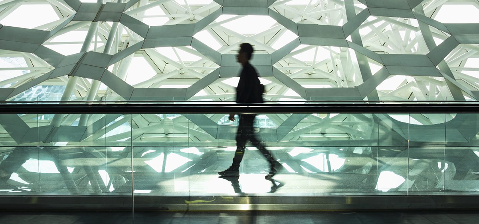 Man walking alone in modern corridor hallway