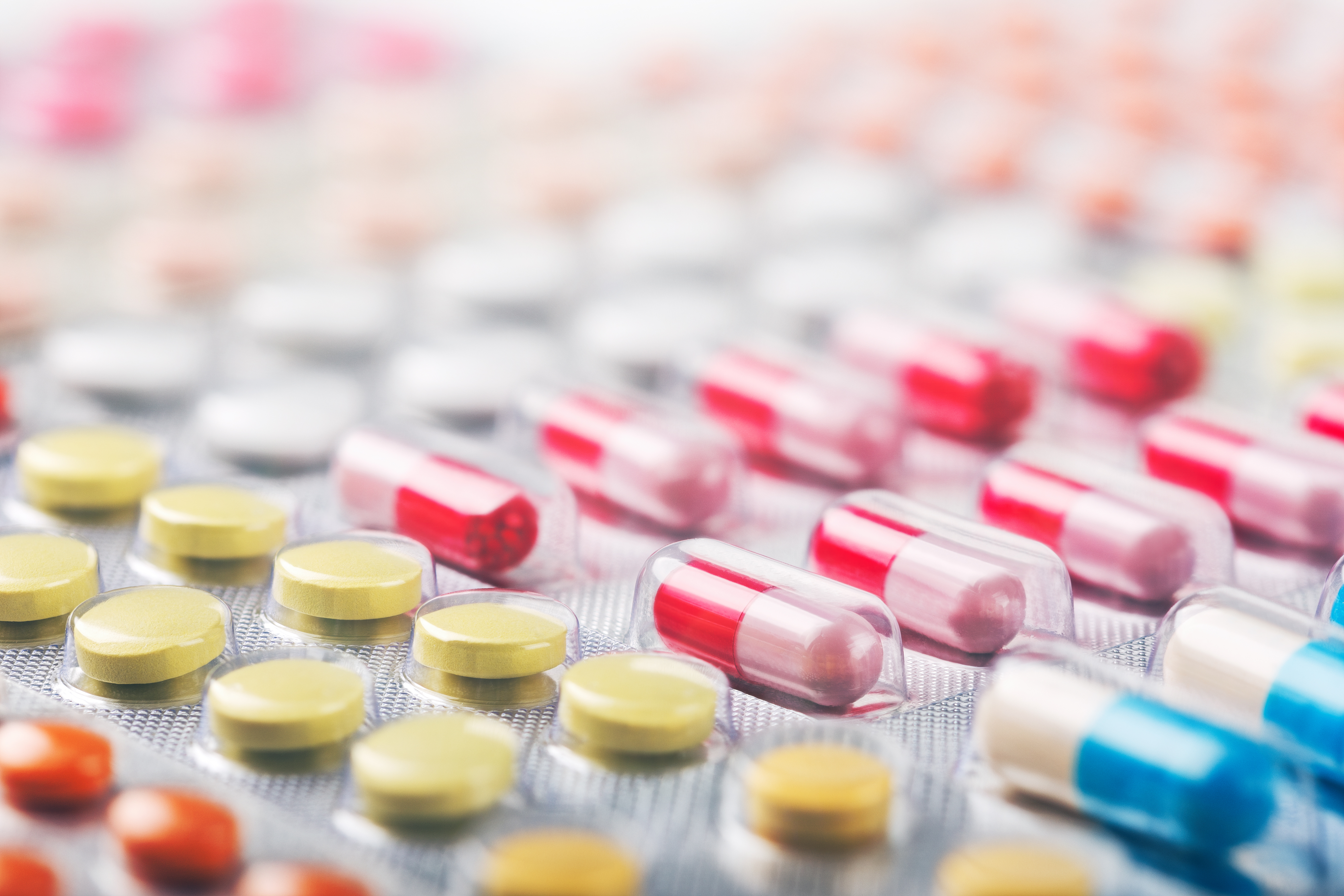 Heap of medical pills in white, blue and other colors. Pills in plastic package. Concept of healthcare and medicine.